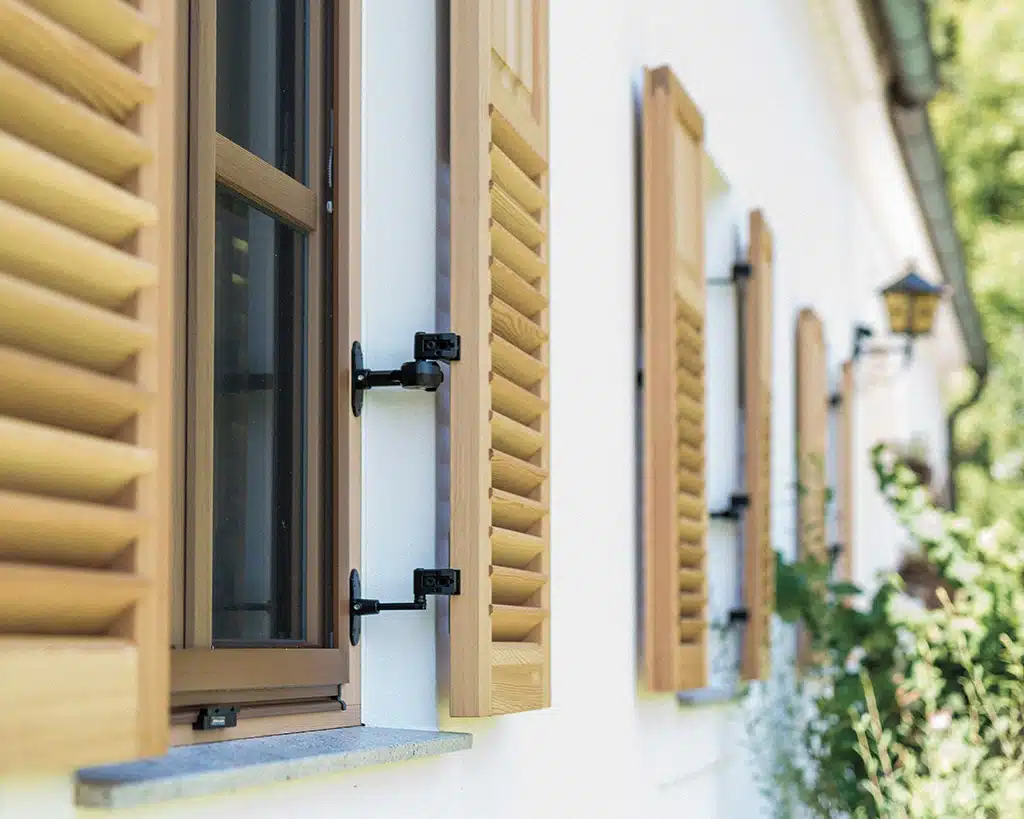 Klassische Fensterläden aus Holz an einer weißen Hauswand als traditioneller und funktionaler Sonnenschutz für Fenster.